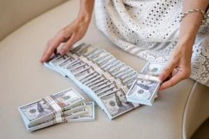 A woman confidently holding a large sum of money, symbolizing financial empowerment and overcoming fears associated with discussing personal finances.