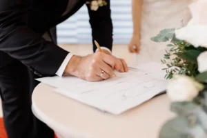 A joyful couple, signing official marriage documents. The setting highlights the significance of legal agreements in marriage, such as prenuptial agreements, wills, and trusts, reinforcing the importance of financial planning and asset protection.