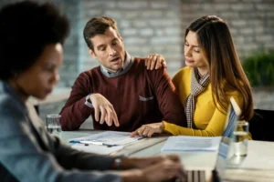 Mid-adult couple reviewing a mortgage agreement with a real estate agent, highlighting the importance of considering a separate revocable living trust for financial security and asset protection.