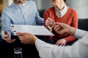 Closeup of unrecognizable couple signing a contract with financial advisor