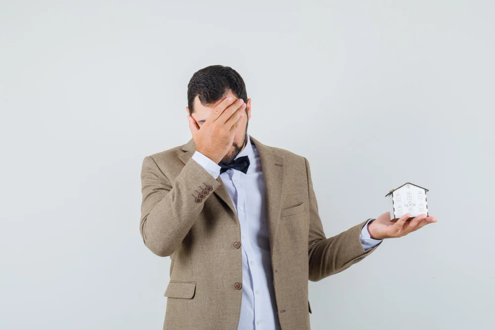 Concerned young single man in suit holding miniature house, reflecting on the importance of estate planning for individuals without dependents.
